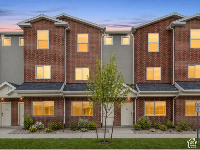 Brick exterior facade with contrasting gray siding accents, dark shingled roof, white trim details, and front landscaping
