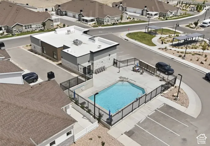 Community swimming pool with surrounding fence, adjacent building with flat roof, and nearby parking area