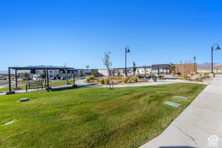 Expansive grassy area featuring a bocce ball courts, concrete pathway, multiple pergolas, and decorative lampposts