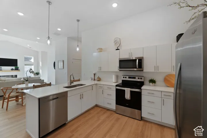 Kitchen featuring white cabinetry, stainless steel appliances, white countertops, wood-finish flooring, and recessed lighting