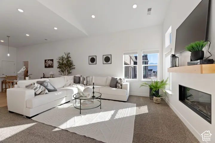 Spacious living area featuring 11' high ceilings, recessed lighting, large windows, a built-in fireplace, and carpeted flooring