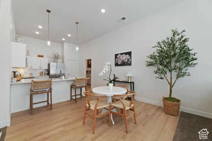 Open-concept living area featuring wood-finish flooring, recessed lighting, and a kitchen with white cabinetry