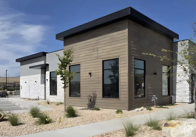 Modern exterior featuring horizontal wood-look siding, white stacked stone accents, flat roofline, and black-framed windows
