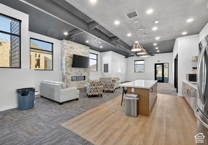 Spacious common area featuring a stone-clad fireplace, recessed lighting, and exposed ductwork