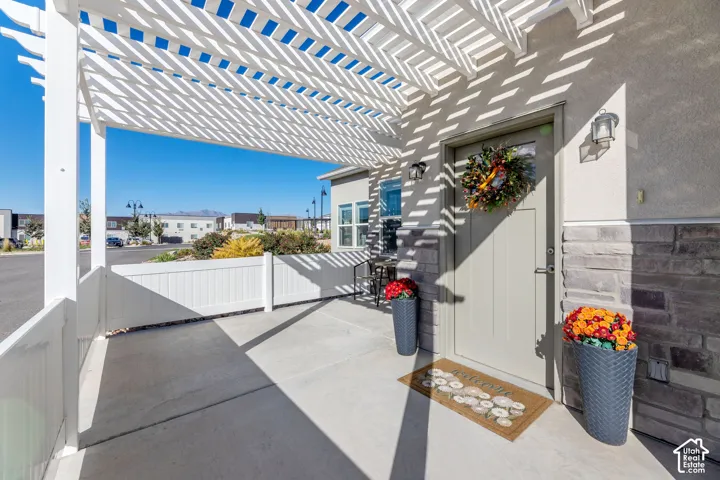 Covered concrete patio featuring a white pergola