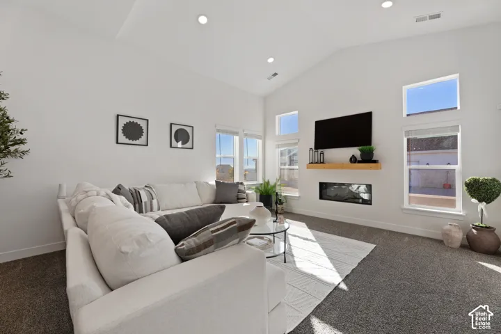 Vaulted ceilings with recessed lighting, integrated electric fireplace, wood-finish mantel, and multiple windows