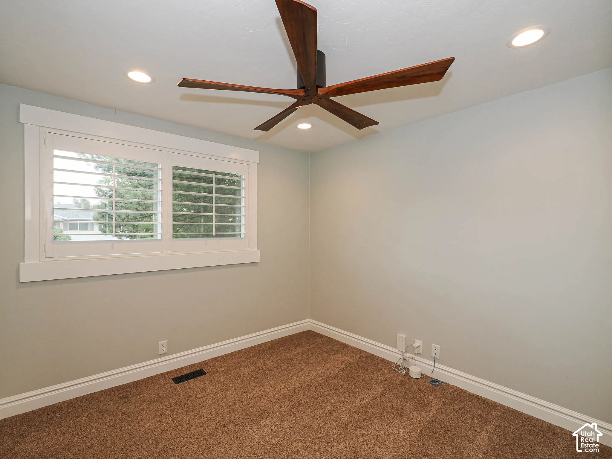 Recessed ceiling lighting, a wood-blade ceiling fan, plantation shutters, and textured carpeting