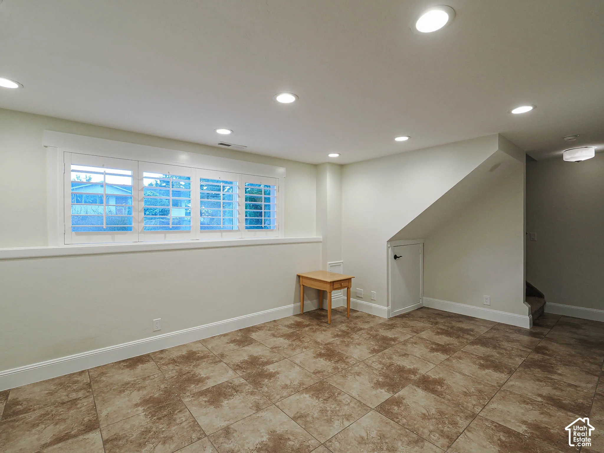 Recessed lighting, tile flooring, window with shutters, under-stair storage, and a light-colored wall finish