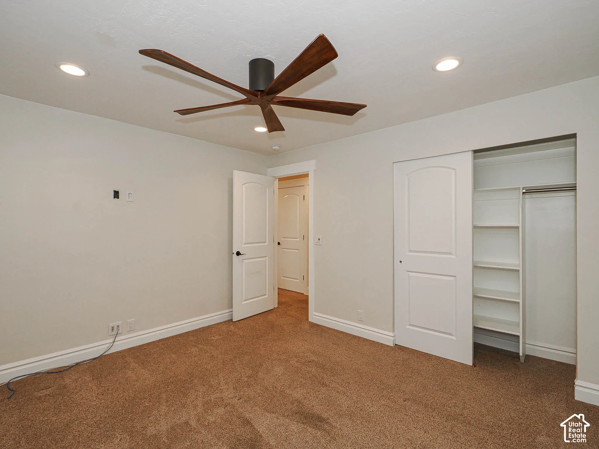 Wood-finish ceiling fan, recessed lighting, white interior doors, and built-in closet shelving