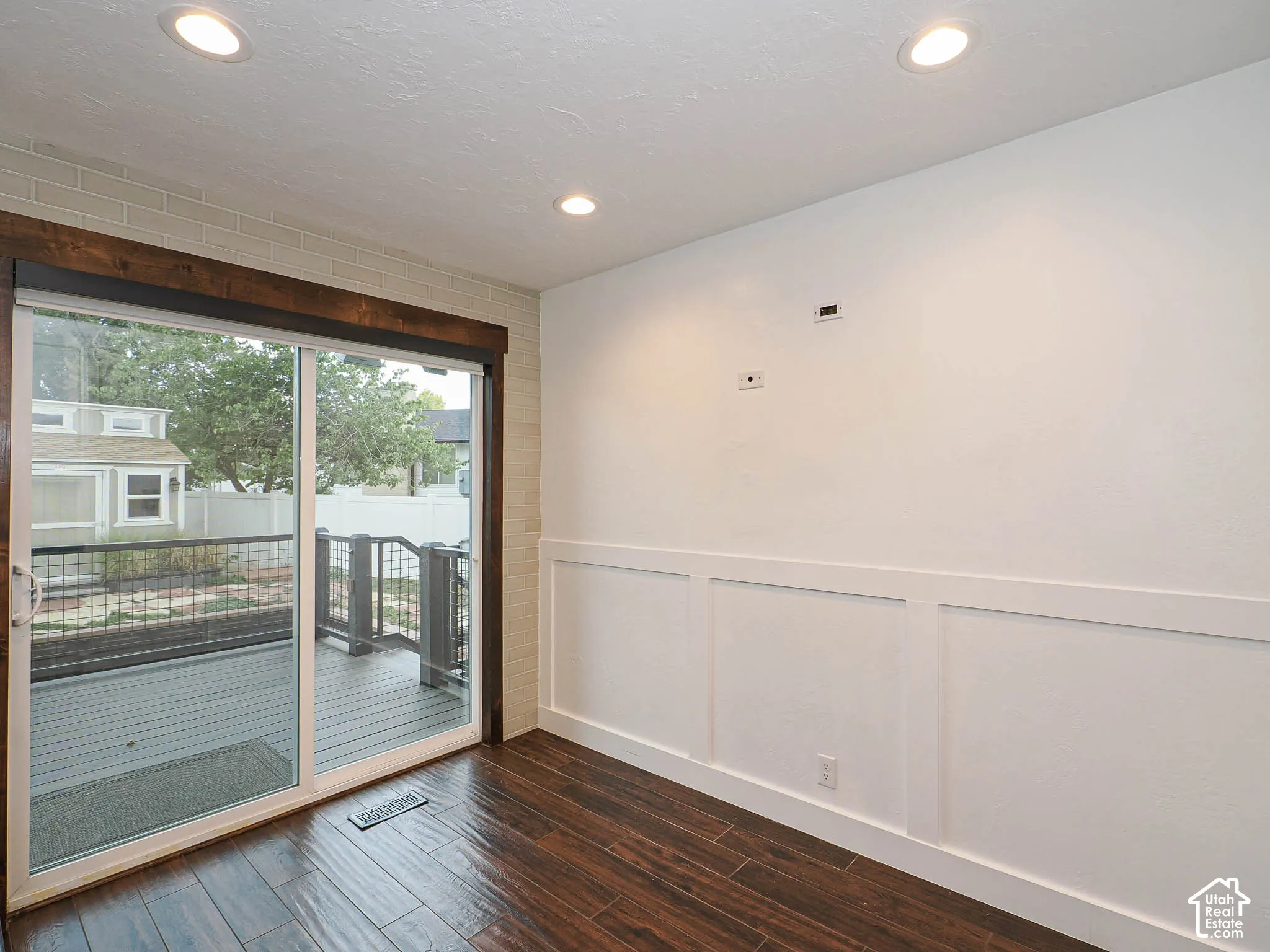 Wood-finish flooring, sliding glass door, recessed lighting, and decorative wall paneling
