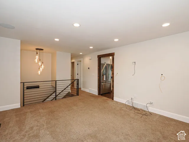 Recessed ceiling lighting, carpet flooring, contemporary chandelier, stainless steel refrigerator, and wood trim doorway