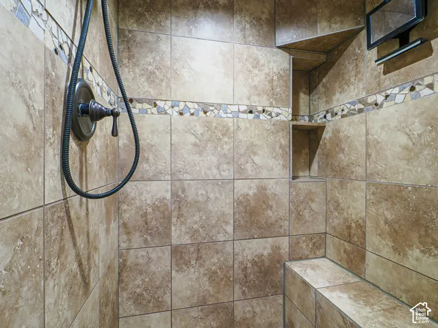 Tiled shower featuring a built-in bench, recessed niches, decorative mosaic band, and bronze-finish fixtures