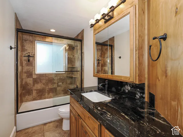 Built-in vanity with wood cabinetry, black granite-style countertop, and integrated rectangular sink