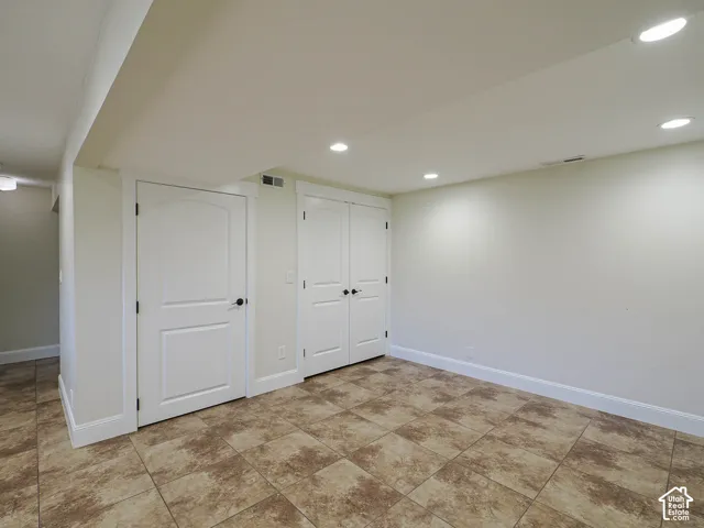 Recessed lighting, tile flooring, interior doors with arch details, white trim, and light-toned walls
