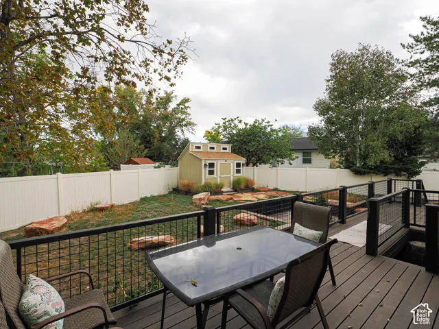Expansive backyard featuring a composite wood deck with black metal railing, a detached storage shed, and a privacy fence