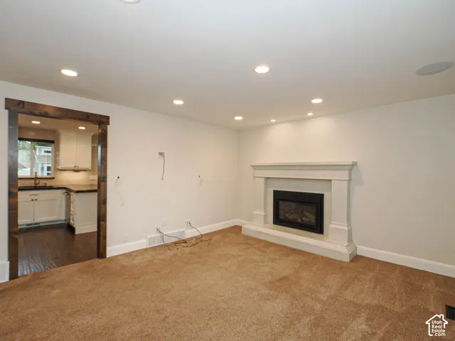 Recessed lighting, built-in fireplace with mantel, ceiling-mounted speaker, and wood-finish door trim
