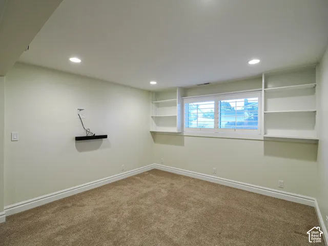 Recessed lighting, built-in shelving, window with white trim, wall-to-wall carpeting, and white baseboard molding