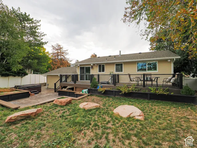 Expansive outdoor deck with a metal railing system, sliding glass door access, and an adjacent patio with a built-in spa