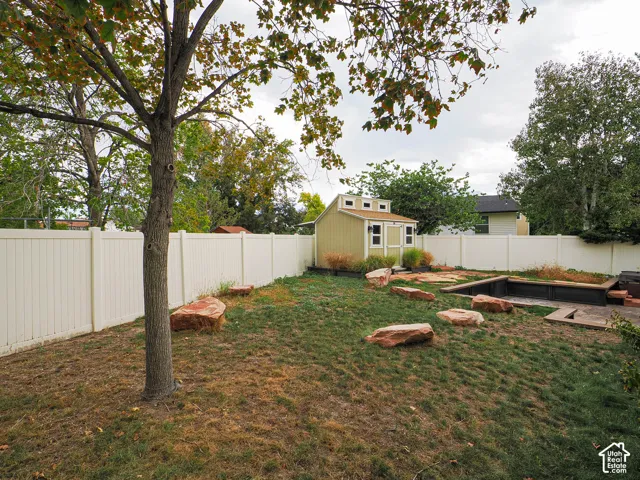 Expansive outdoor space featuring a detached storage shed, a privacy fence, and multiple large stone elements