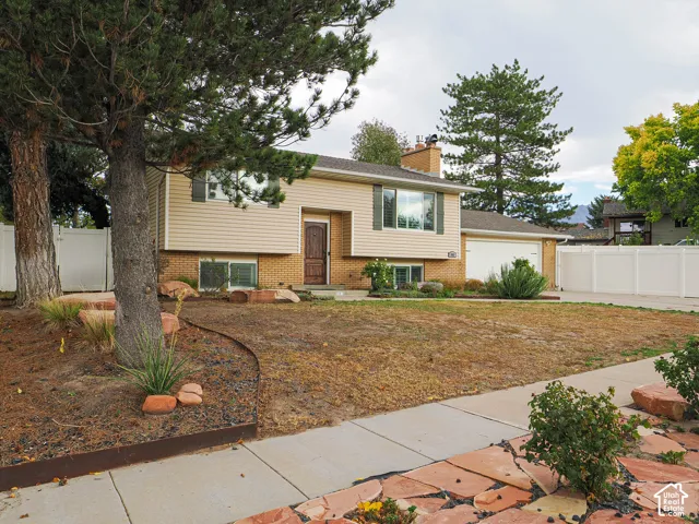 Split-level residence featuring a brick and siding exterior, an attached two-car garage, and a wood-paneled front door