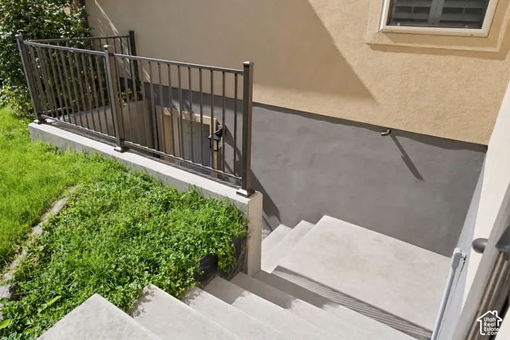 Concrete exterior steps with a metal handrail, leading to a lower level entrance