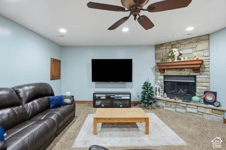 Stone-faced fireplace with a wood mantel, recessed lighting, and a ceiling fan