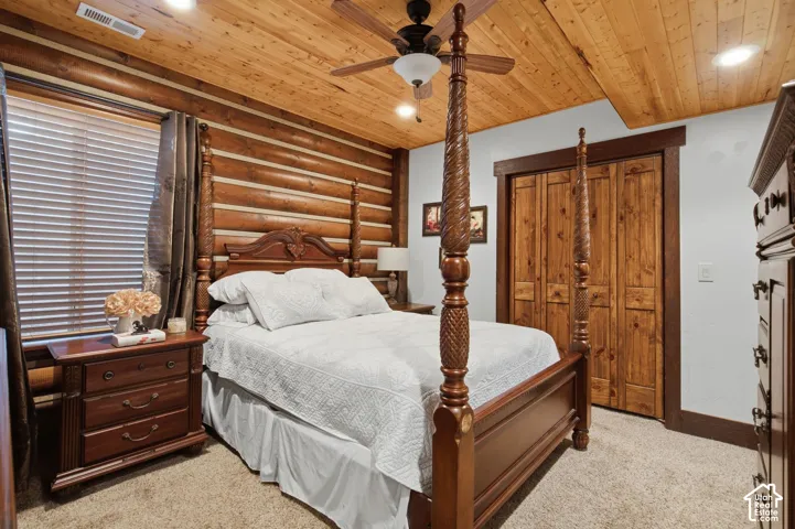 Log accent wall, wood-paneled ceiling, recessed lighting, wood-finish bi-fold closet doors, and a ceiling fan with light fixture