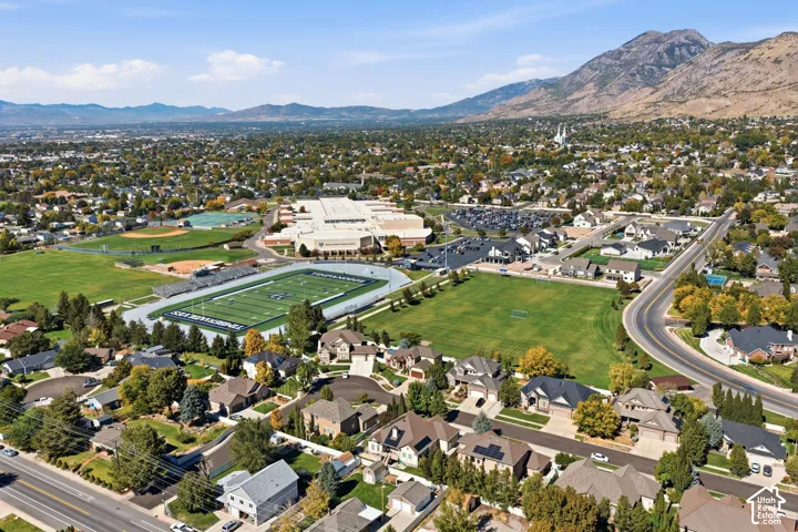 Expansive neighborhood with mature trees, established residential properties, prominent athletic fields, and mountain backdrop