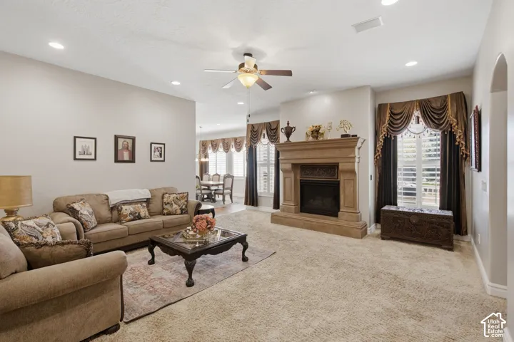 Recessed lighting, ceiling fan, fireplace with detailed mantel, arched doorway, and window with plantation shutters