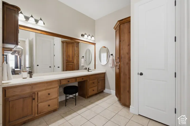 Elongated vanity with dual integrated sinks, ample storage cabinetry, and a dedicated vanity seating area