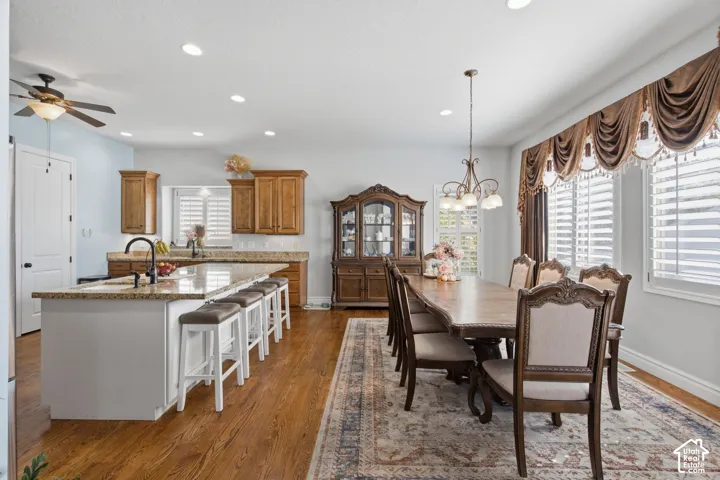 Kitchen island with granite countertop and seating, wood-finish flooring, custom window treatments, recessed lighting, and a ceiling fan