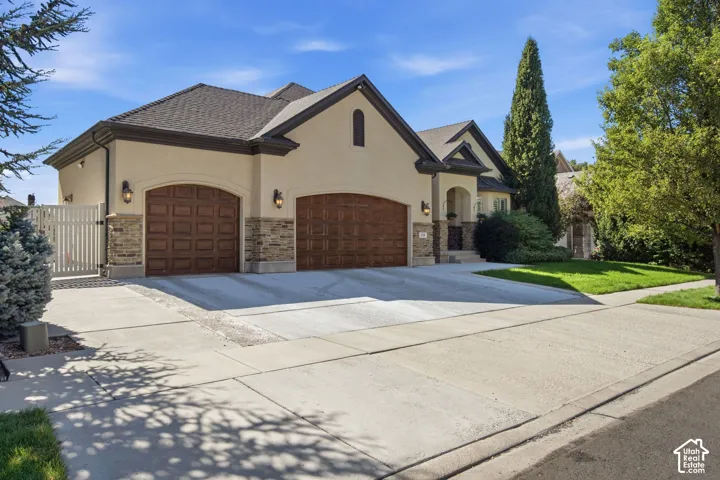 Stucco exterior with stone accents, arched garage doors, and a concrete driveway