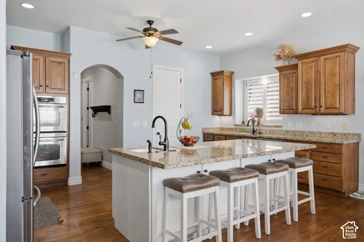 Kitchen featuring wood-finish flooring, stainless steel double ovens, granite countertops, and wood cabinetry with crown molding