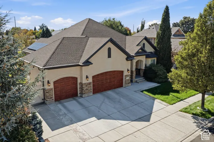 Stucco exterior with stone accents, arched garage doors, a covered entry, and a concrete driveway