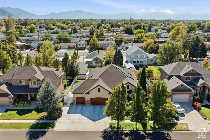 Stucco exterior with a pitched roof, attached two-car garage, mature landscaping, and a mountain backdrop