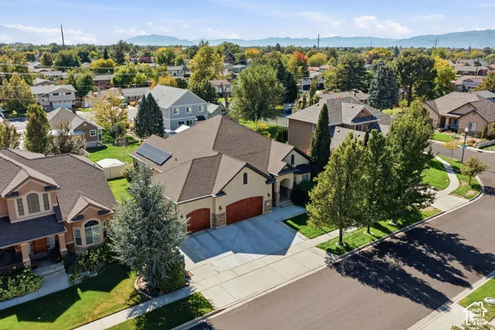 Stucco exterior with a multi-car garage, concrete driveway, and mature landscaping