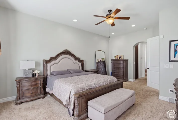 Plush carpet flooring, recessed lighting, ceiling fan light fixture, and an arched doorway