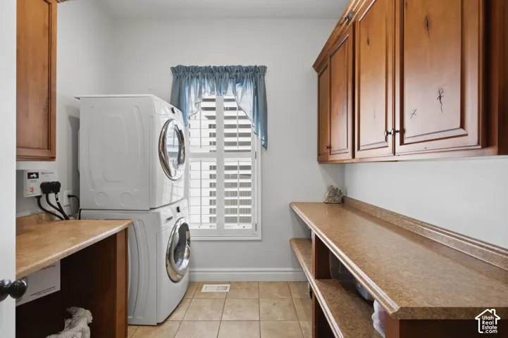 Wood-finish cabinetry paired with ample countertop space, a window with plantation shutters, and tiled flooring