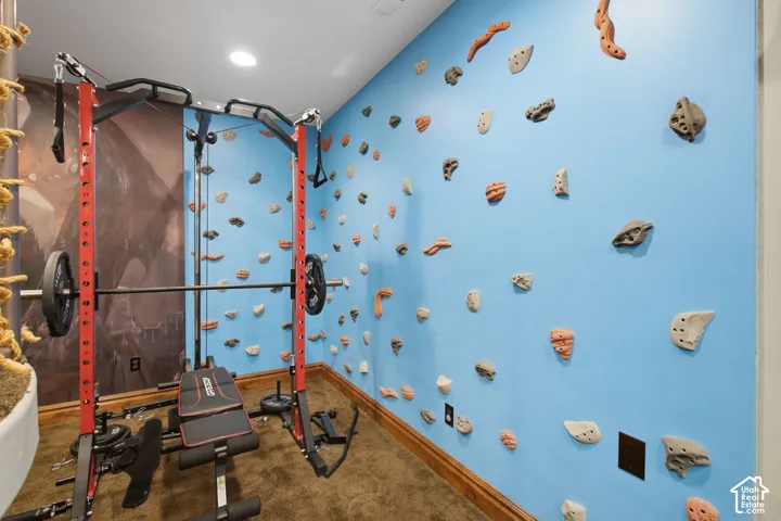 Indoor climbing wall with varied holds, wood-finish base trim, and recessed lighting