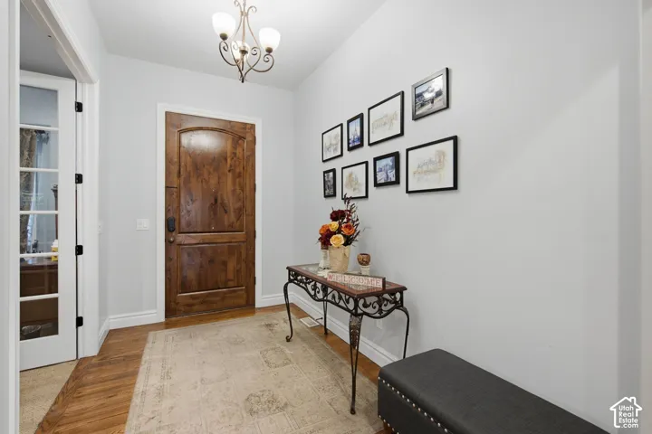 Warm wood-finish flooring, a decorative chandelier, and a solid wood entry door
