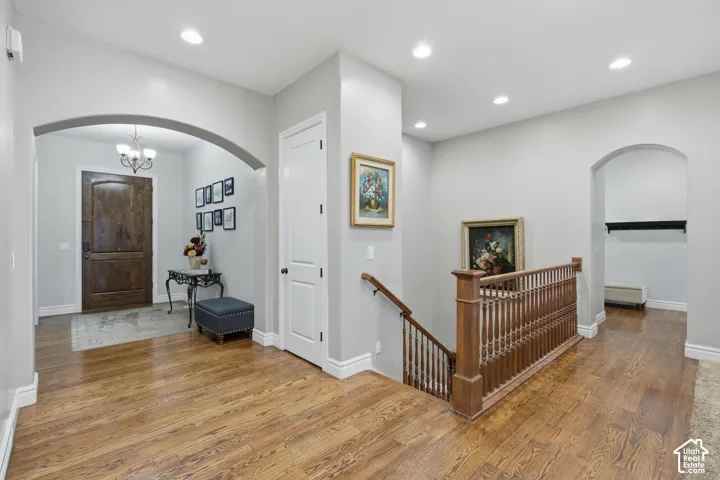 Hardwood flooring extending throughout, recessed lighting, arched doorways, white trim, and a wood staircase with balusters