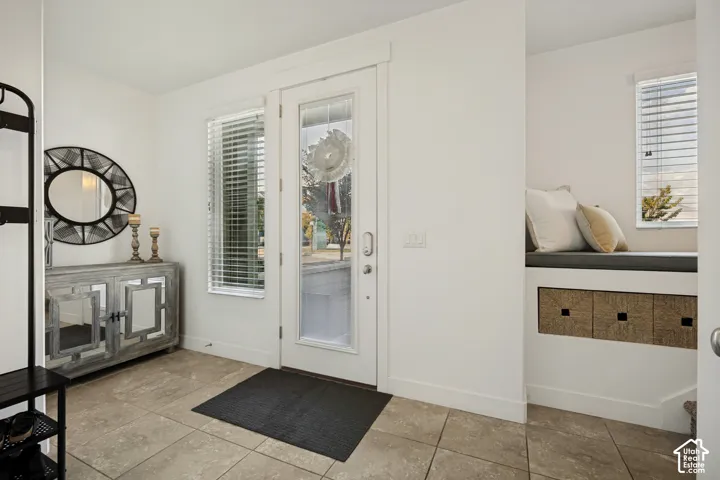 Tile flooring, built-in window bench, large glass-paneled entry door, and a rectangular window with blinds