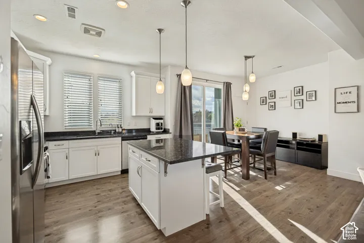 Kitchen featuring wood-finish flooring, white cabinetry, dark countertops, and stainless steel appliances