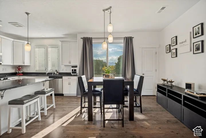 White cabinetry with dark countertops, stainless steel appliances, and wood-finish flooring