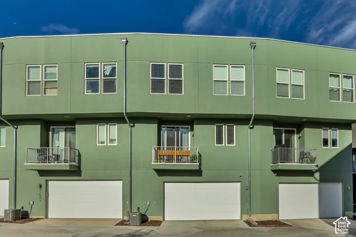 Contemporary exterior with multiple windows, balconies with metal railings, and integrated garage doors