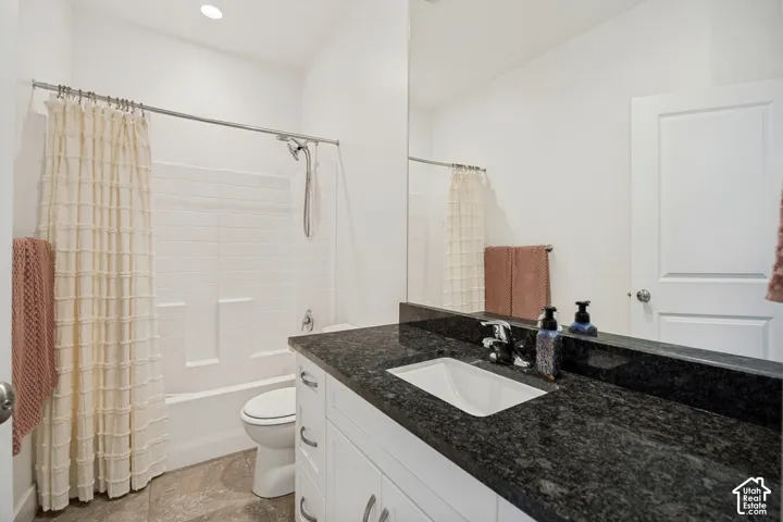 White vanity with an integrated rectangular sink, dark speckled countertop, and chrome faucet