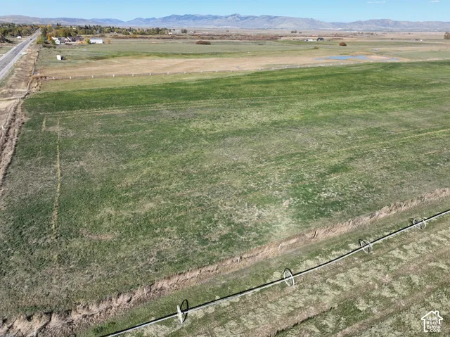 Expansive agricultural land featuring a verdant field, mountain backdrop, and irrigation system