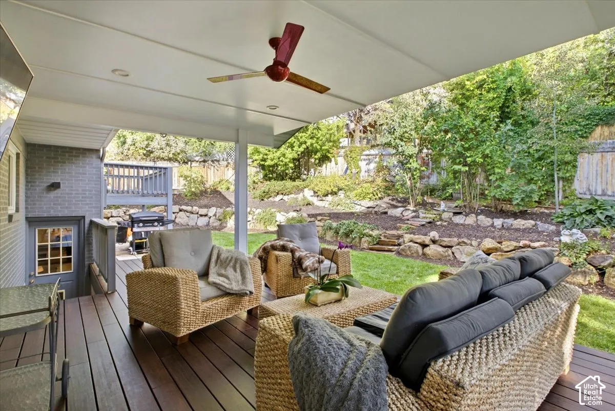 Covered outdoor living space featuring dark wood-finish decking, recessed lighting, and a ceiling fan