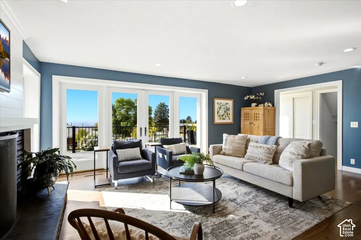 Bright living area with wood-finish flooring, a fireplace with a stone surround, recessed lighting, and a multi-panel glass door leading to an exterior balcony