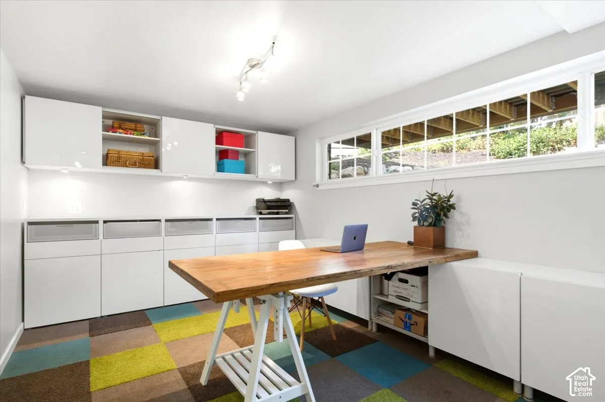 Built-in cabinetry and shelving, track lighting, wood-finish desktop, and multi-paned horizontal window